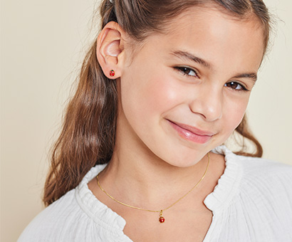 Mädchen trägt goldenen Schmuck mit Marienkäfer Motiv
